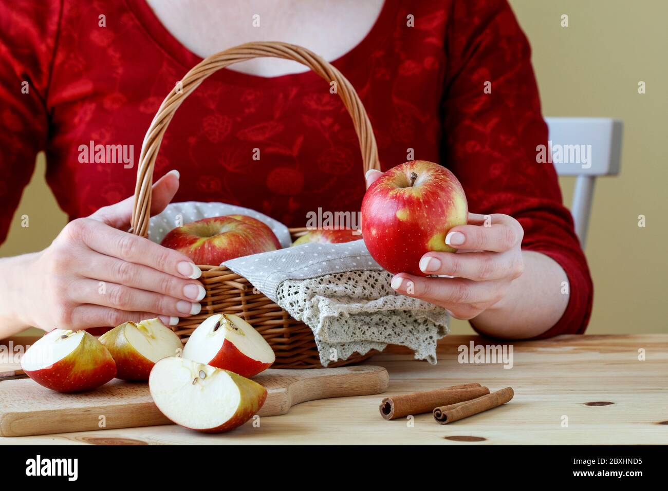 Junge Frau in roter Bluse hält einen geschnittenen Apfel. Gesunde Ernährung Stockfoto