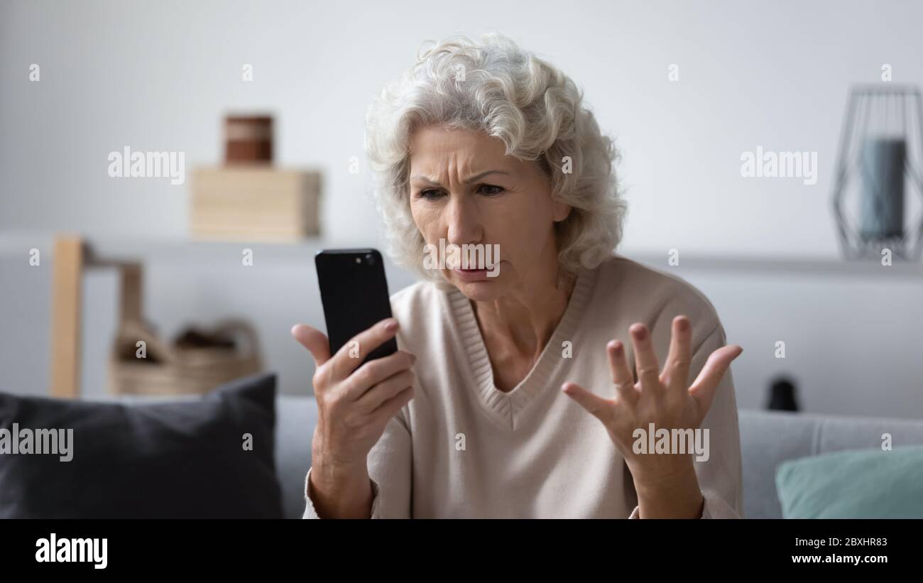 Wütend ältere Frau frustriert durch Smartphone-Probleme Stockfoto