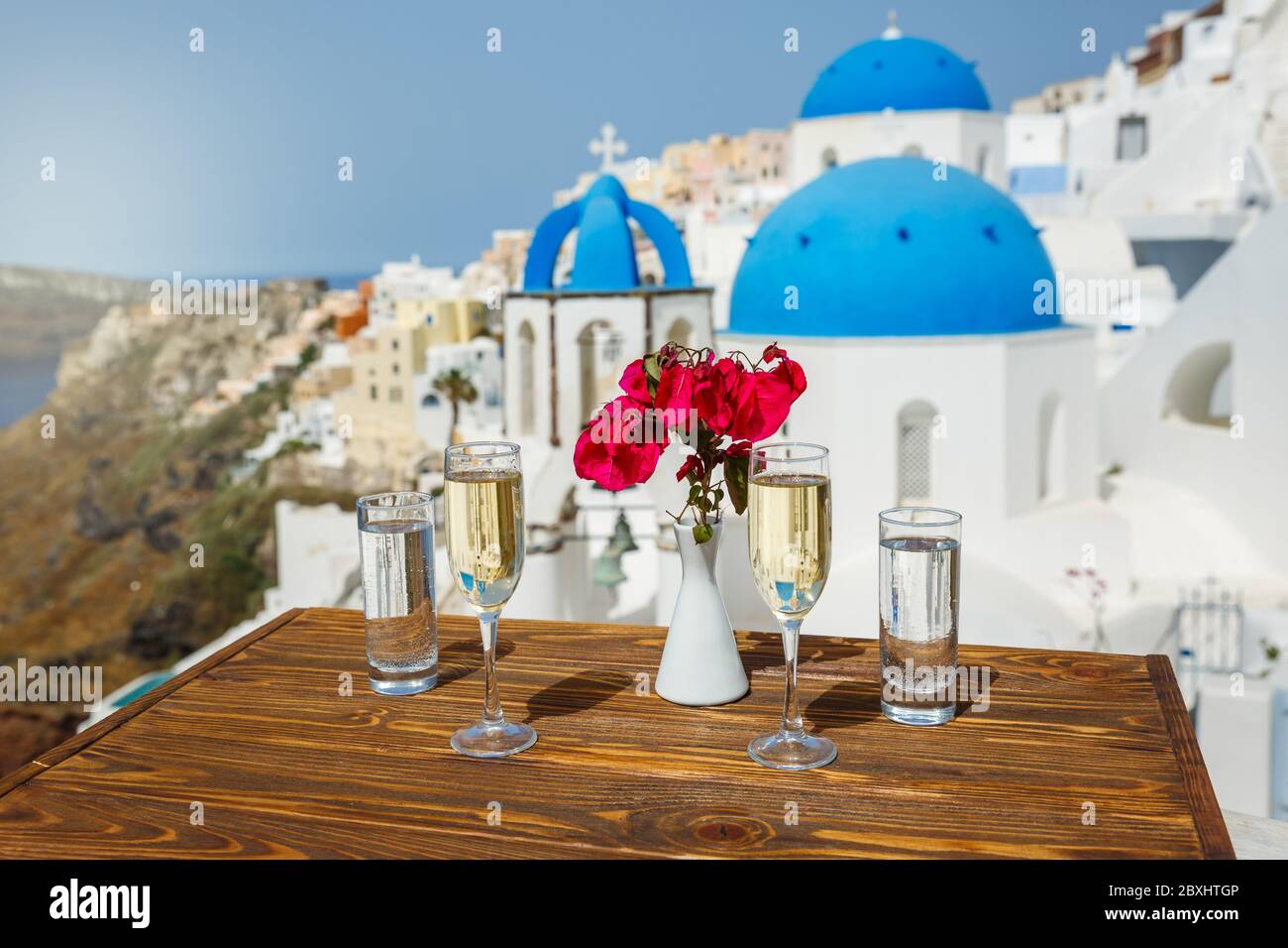 Zwei Gläser Weißwein auf dem Tisch, vor der Kulisse der Insel Santorini Stockfoto
