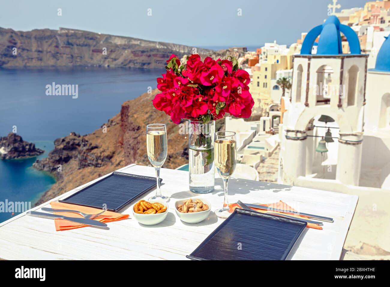 Zwei Gläser Weißwein auf dem Tisch, vor der Kulisse der Insel Santorini Stockfoto