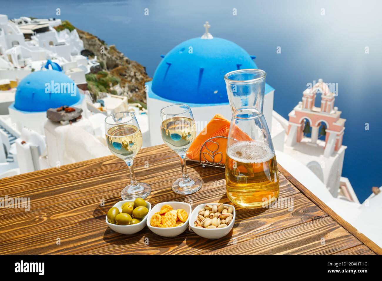 Eine Flasche Wein und zwei Gläser auf dem Tisch, vor der Kulisse der Insel Santorini Stockfoto