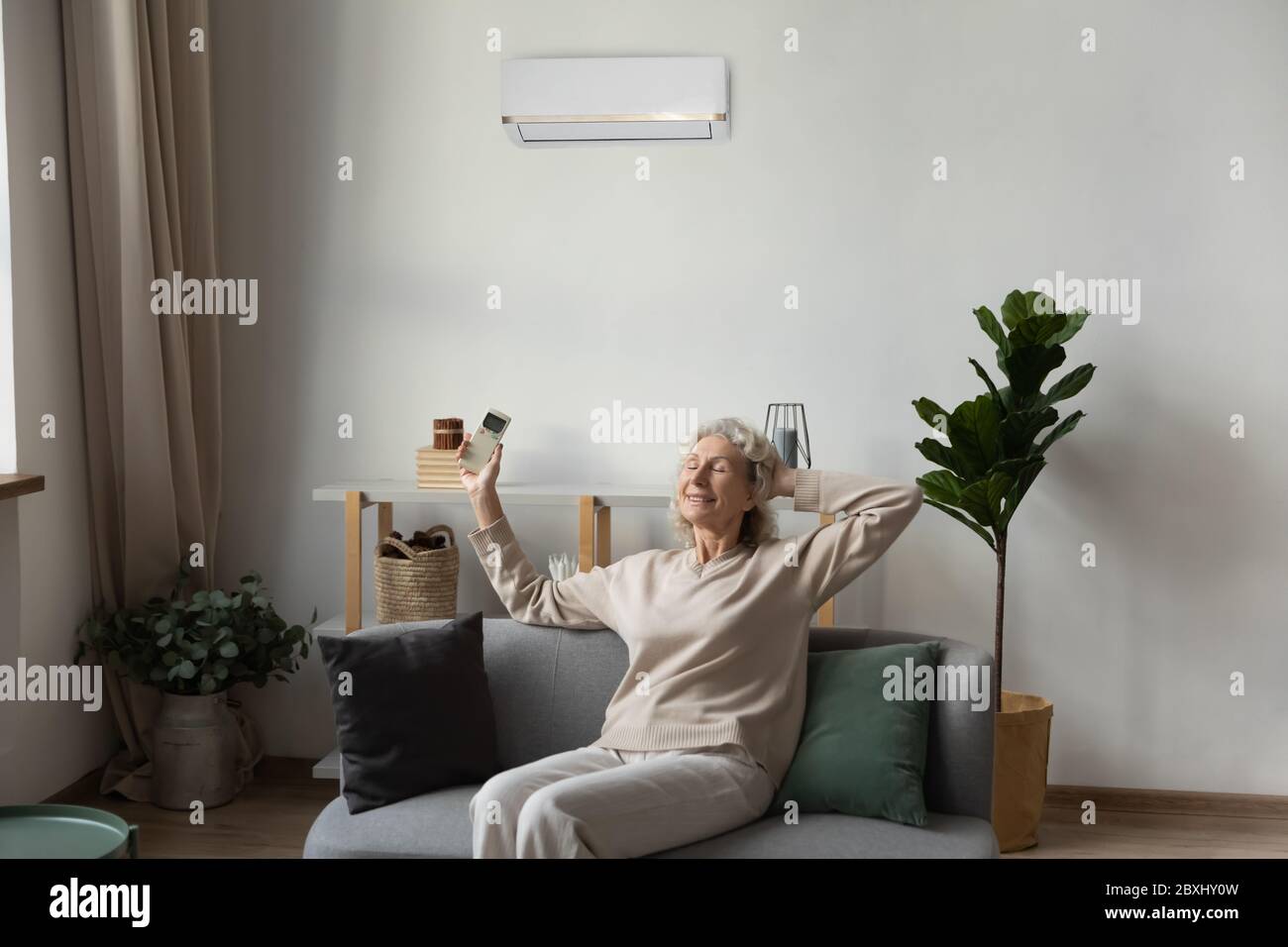 Ältere Frau atmen frische Luft mit AC zu Hause Stockfoto