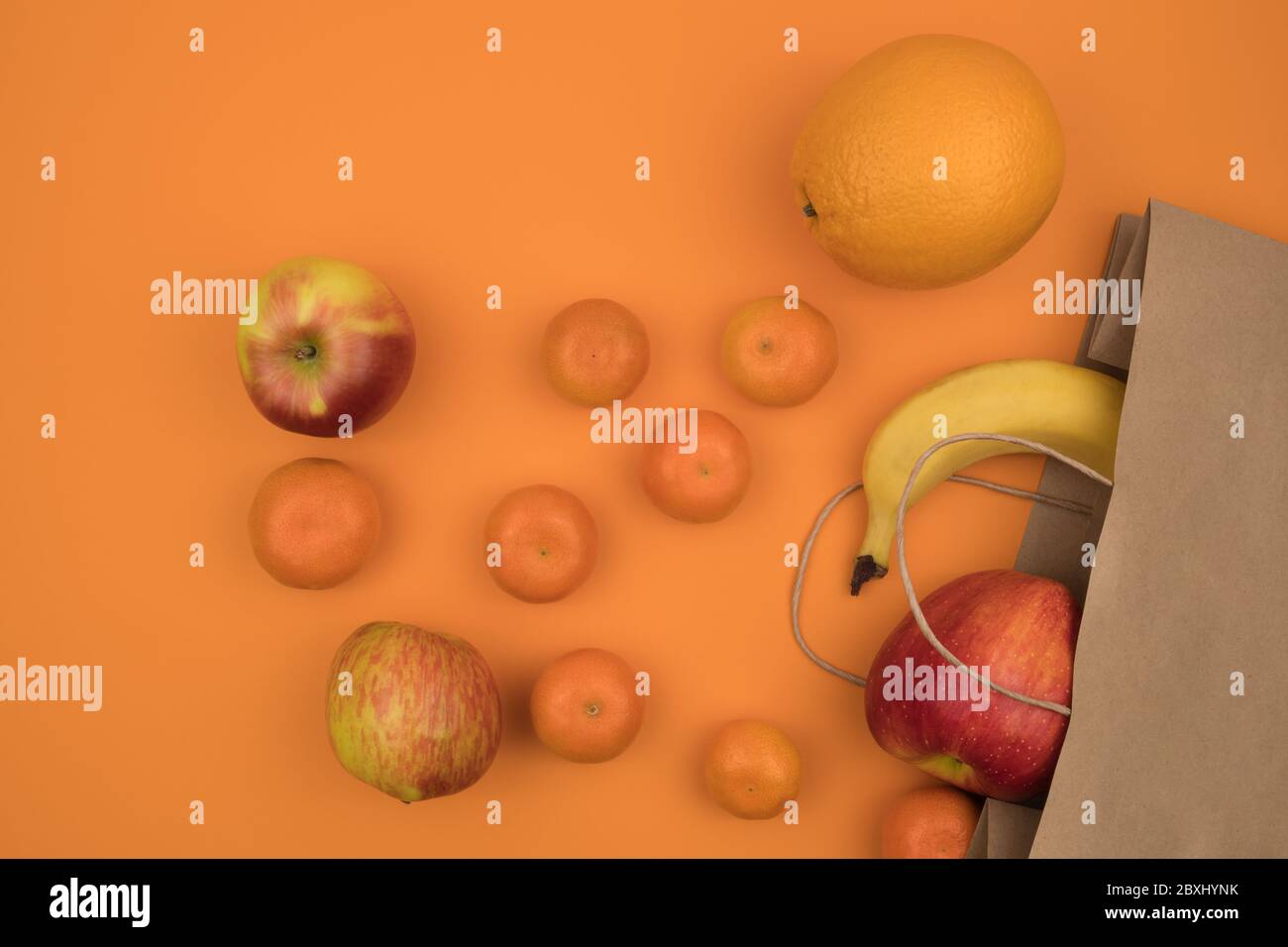 Nützliche Bio-Frucht der ökologischen Papiertüten. Orangefarbener Hintergrund. Stockfoto