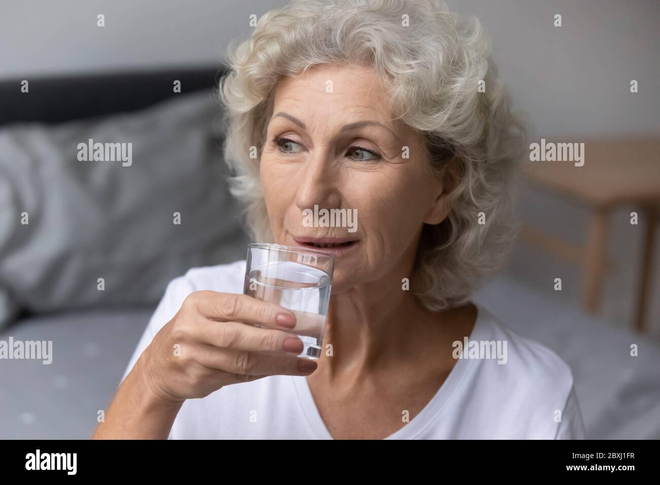 Ältere Frau genießen sauberes stilles Wasser aus Glas Stockfoto