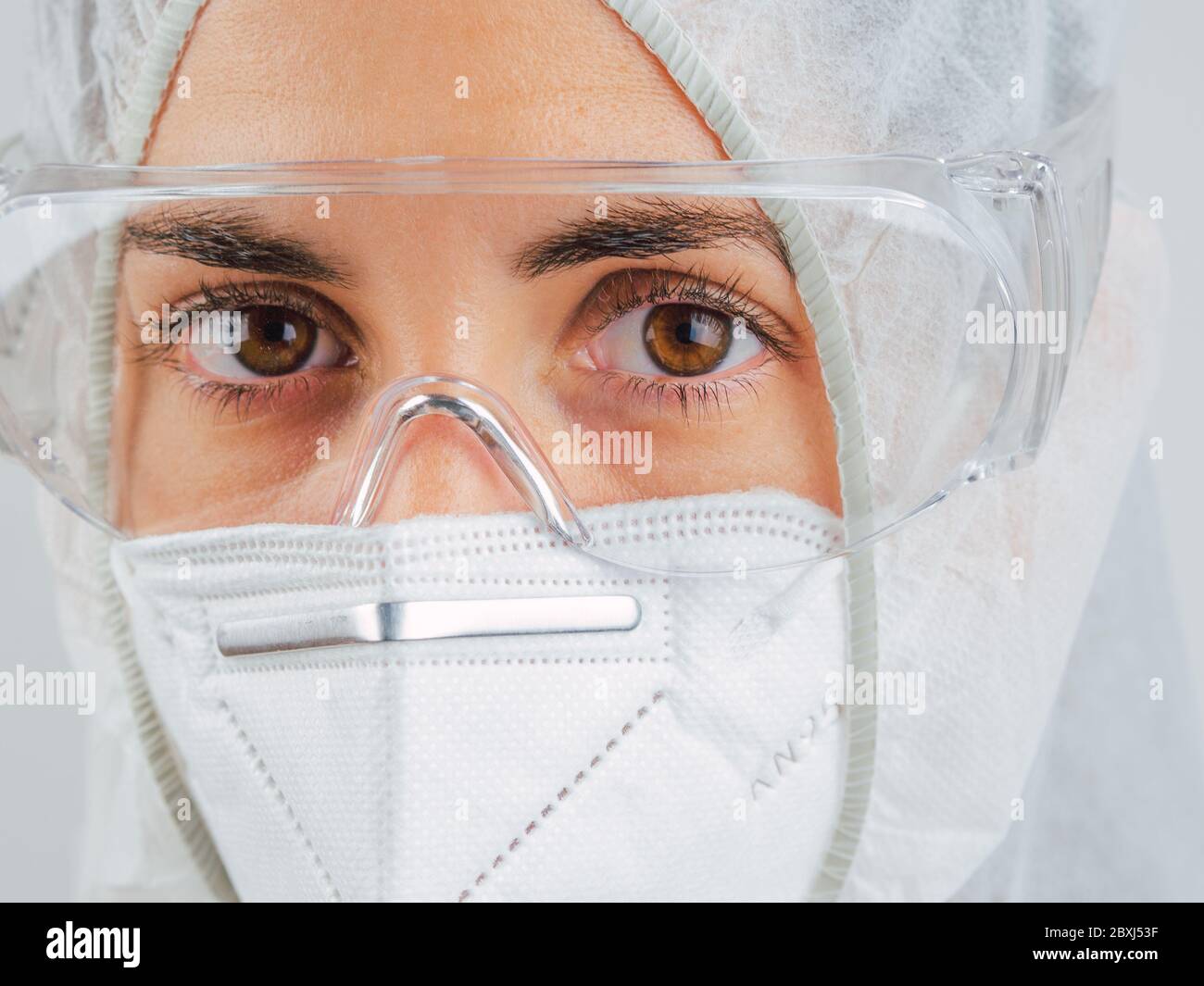 Kaukasischer Arzt. Müde und erschöpft Wissenschaftler oder Krankenschwester tragen Maske und Schutzanzug gegen biologische Gefahren. Zeigen Sie Angst vor der Situation. Koro Stockfoto