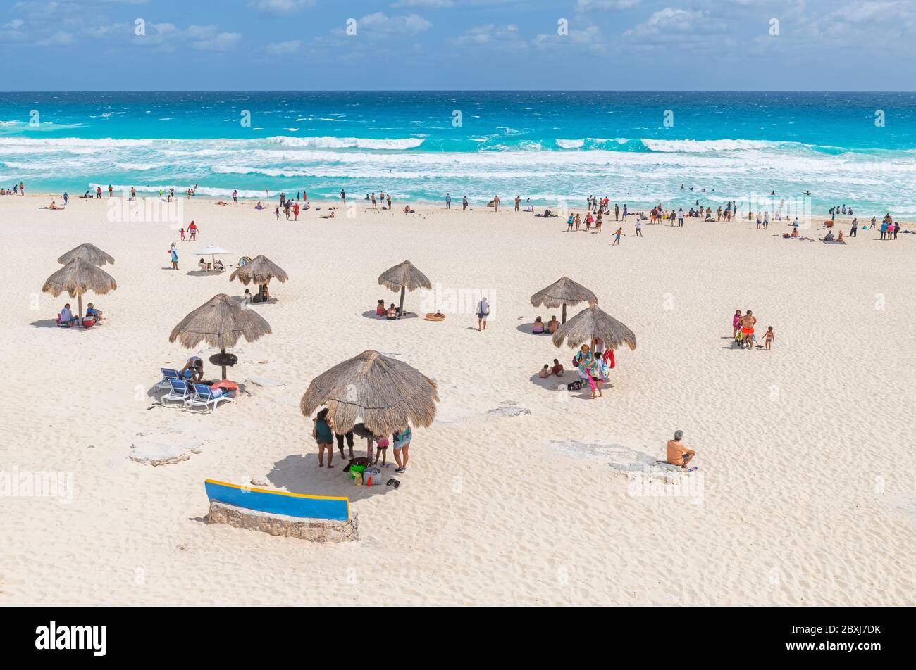 Touristen und Mexikaner auf Playa Delfines unter Schilfschirmen an der Karibik, Cancun, Yucatan Halbinsel, Mexiko. Stockfoto
