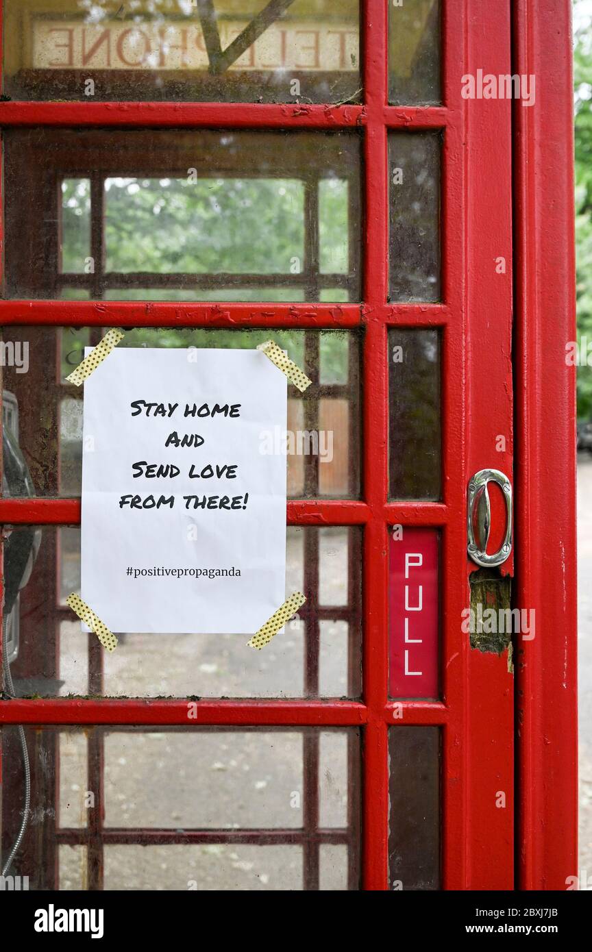 Eine Mitteilung auf einem roten britischen Telefonkasten „Bleiben Sie nach Hause und senden Sie Liebe von dort“. Stockfoto