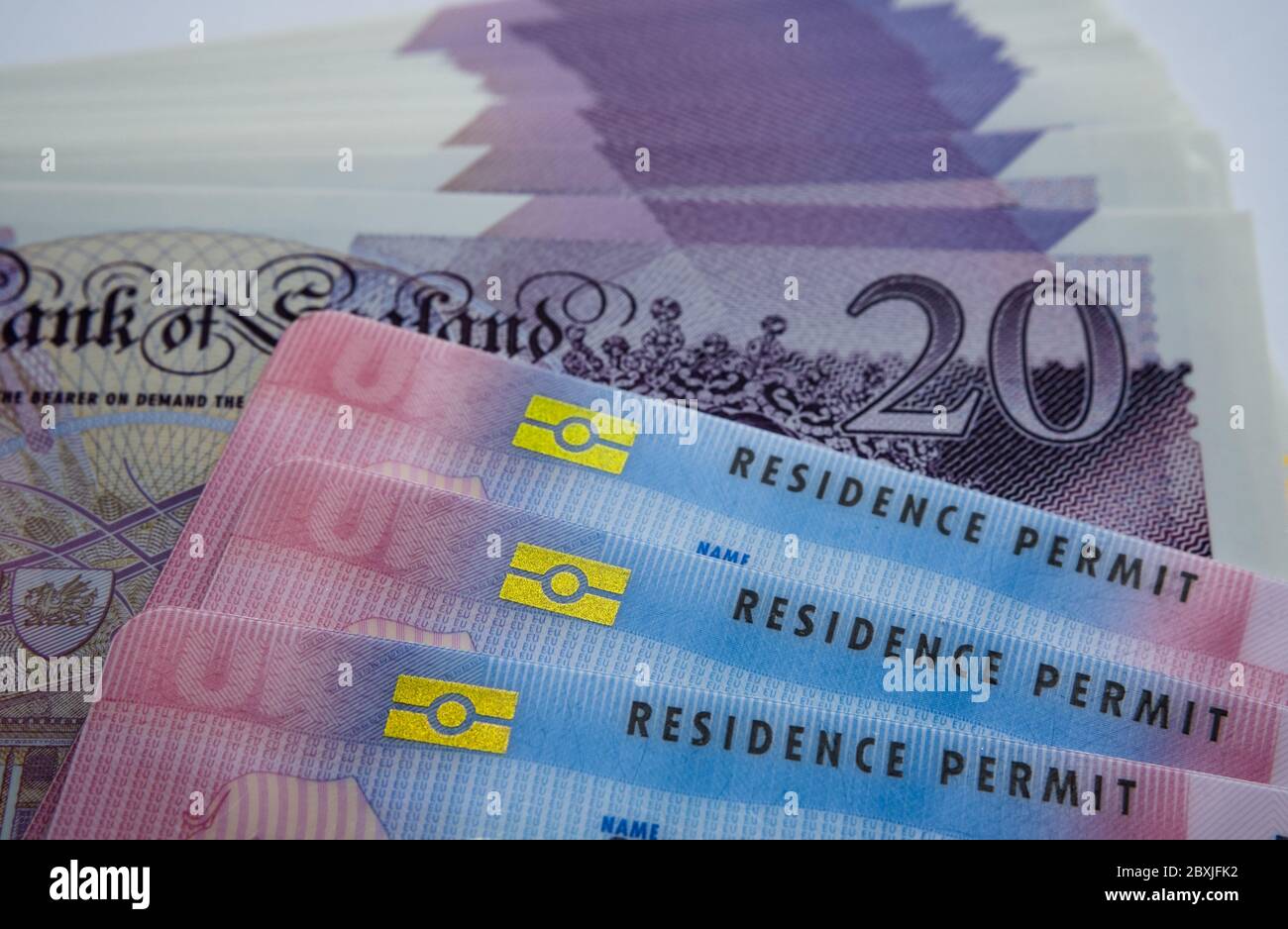 UK biometrische Aufenthaltstitel und 20 Pfund Banknoten. BRP-Karten für Tier 2 Arbeit Visum Einwanderer freigegeben. Konzept Bild für den Preis des Visums. Stockfoto