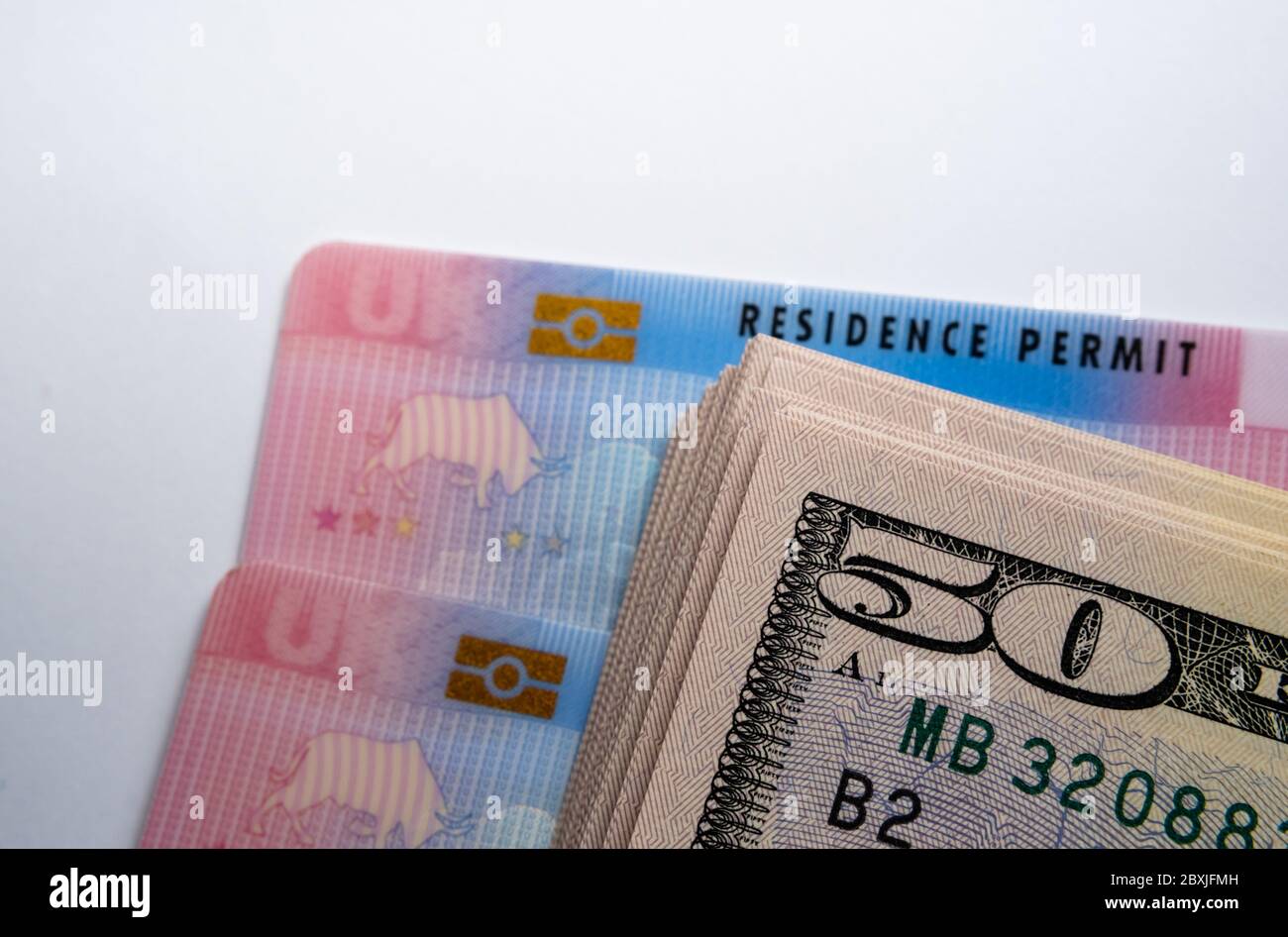 UK biometrische Aufenthaltstitel Karten und Stapel von 50-Dollar-Banknoten. BRP-Karten für Tier 2 Arbeit Visum Einwanderer freigegeben. Konzept Bild für Kosten von Th Stockfoto