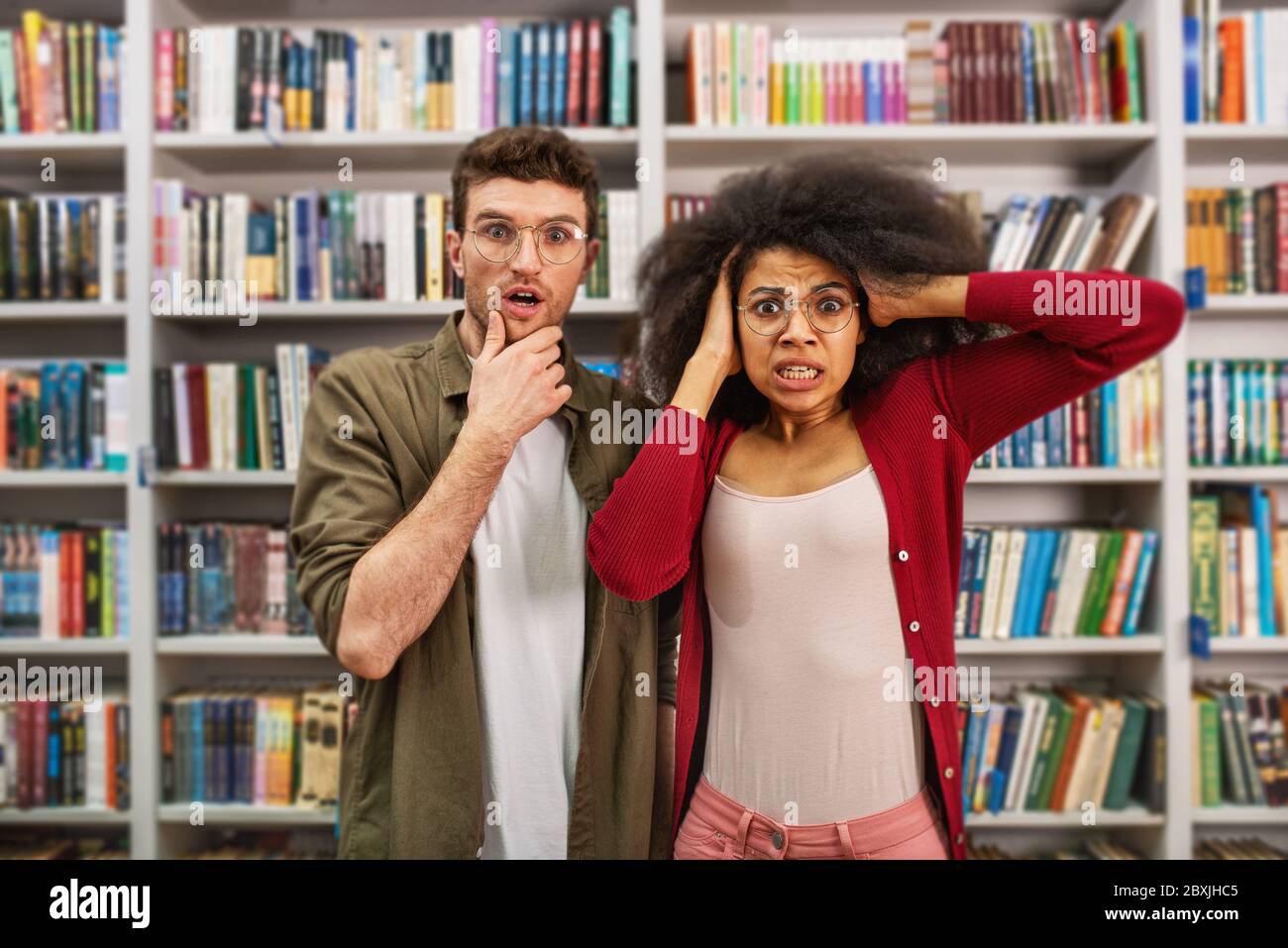 Junger Student mit besorgter Ausdrucksweise in einer Bibliothek Stockfoto