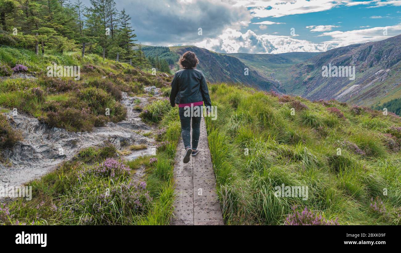 Frau ist auf dem Weg auf dem Gipfel des Berges im Tal von Glendalough, Wicklow Mountains, Irland zu Fuß. Sommertag. Stockfoto