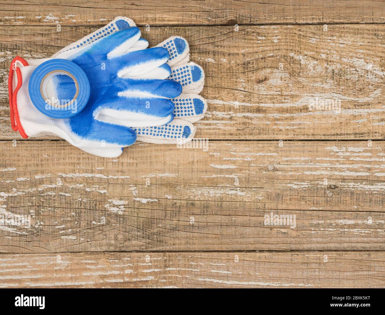 Schutzhandschuhe und Klebeband auf Holzhintergrund. Stockfoto