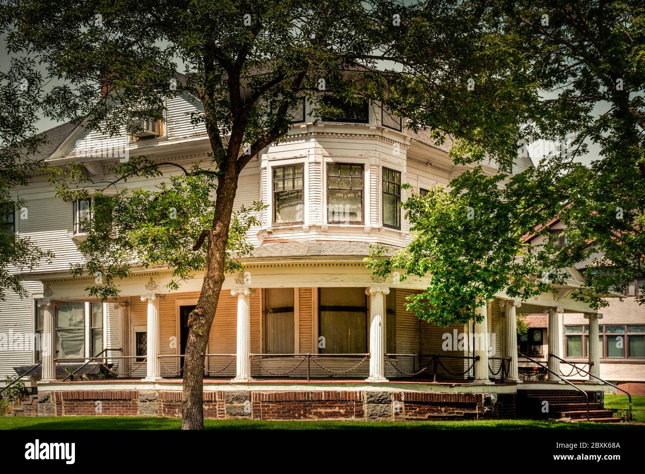 Ein alterndes dreistöckiges Haus im Queen Anne Architekturstil mit seiner umlaufenden Veranda und Kettengliederelementen in St. Cloud, MN, USA Stockfoto