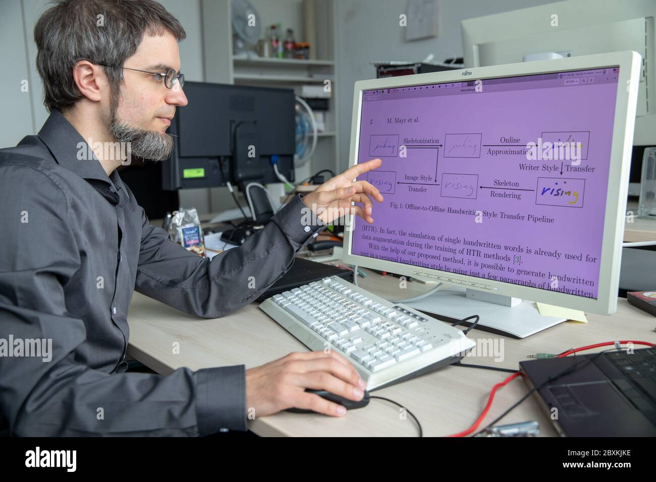 Erlangen, Deutschland. Juni 2020. Vincent Christlein, Informatiker und wissenschaftlicher Mitarbeiter am Lehrstuhl für Mustererkennung an der Universität Erlangen-Nürnberg, erläutert die Schritte der Handschriftimitate durch Software mittels Grafik. Erlangen-Forscher imitieren mit künstlicher Intelligenz die Handschrift. Ein Ziel ist es, Menschen zu ermöglichen, die aufgrund von Verletzungen oder anderen Beeinträchtigungen keine Texte in eigener Handschrift schreiben können. Quelle: Daniel Karmann/dpa/Alamy Live News Stockfoto