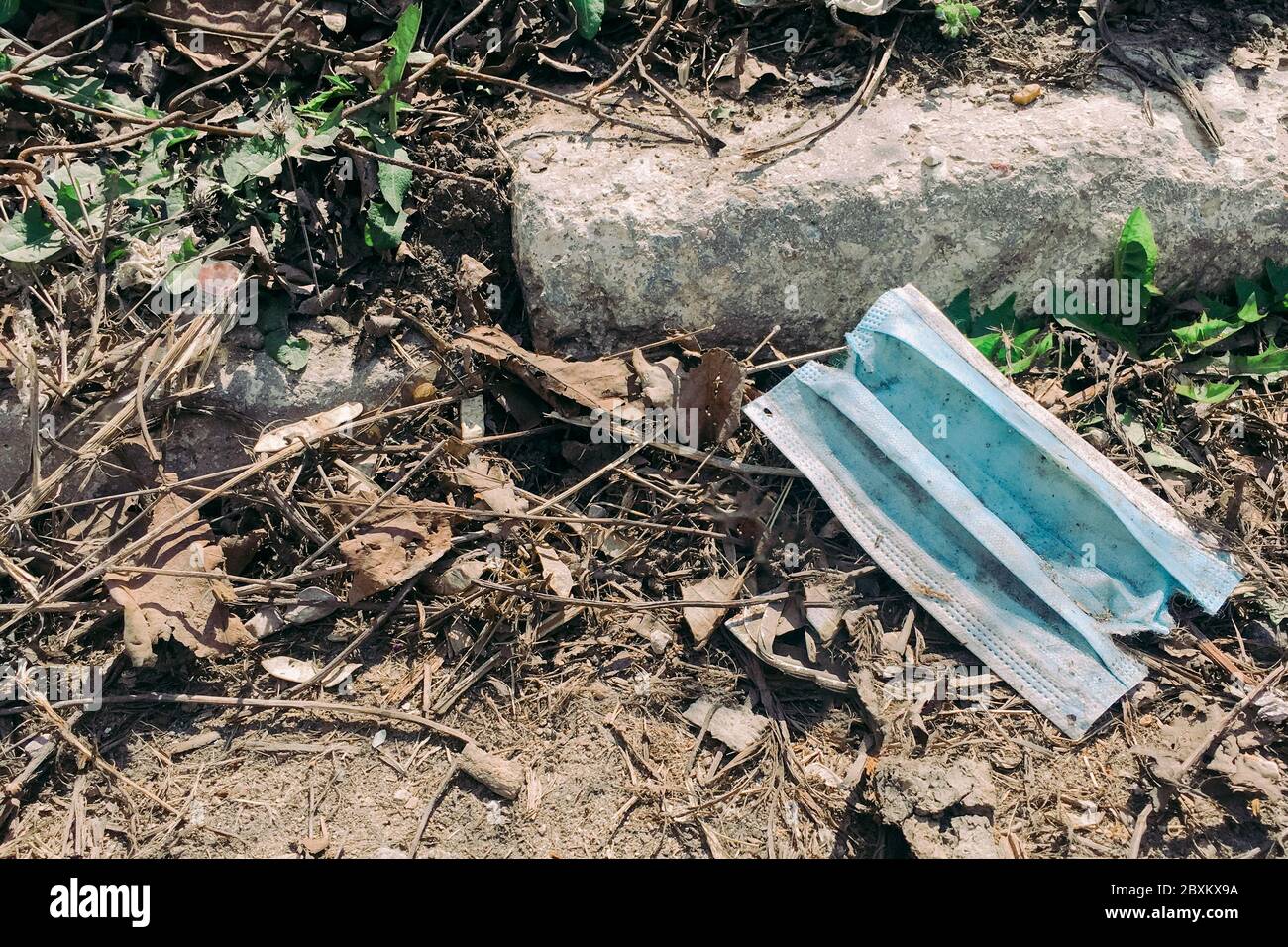Eine gebrauchte medizinische Gesichtsmaske, die während der Covid-19-Pandemie auf den Boden geworfen wurde. Konzept der Umweltverschmutzung Stockfoto