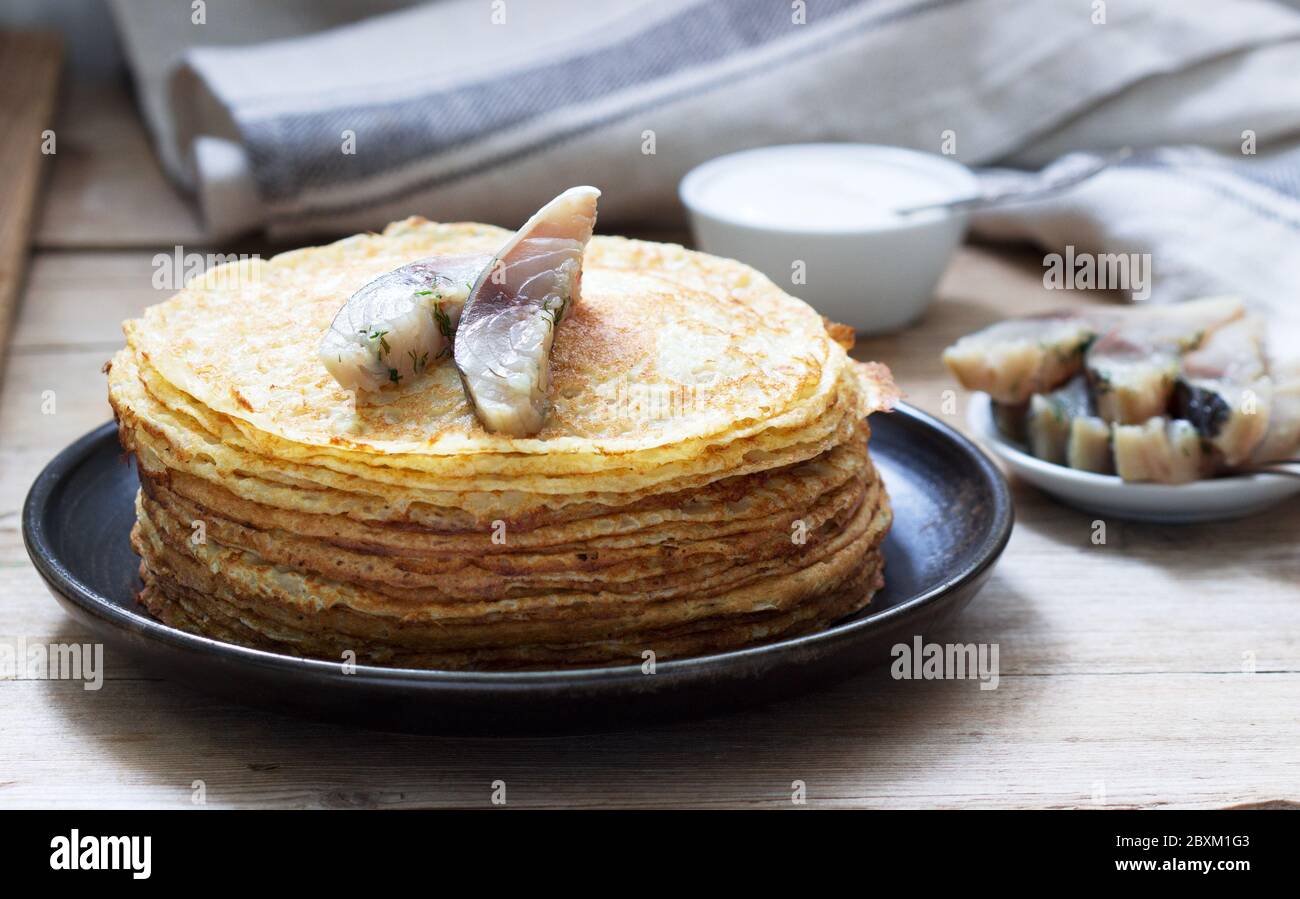 Pfannkuchen mit Glavraks aus Makrele und saurer Sahne auf Holzgrund. Stockfoto