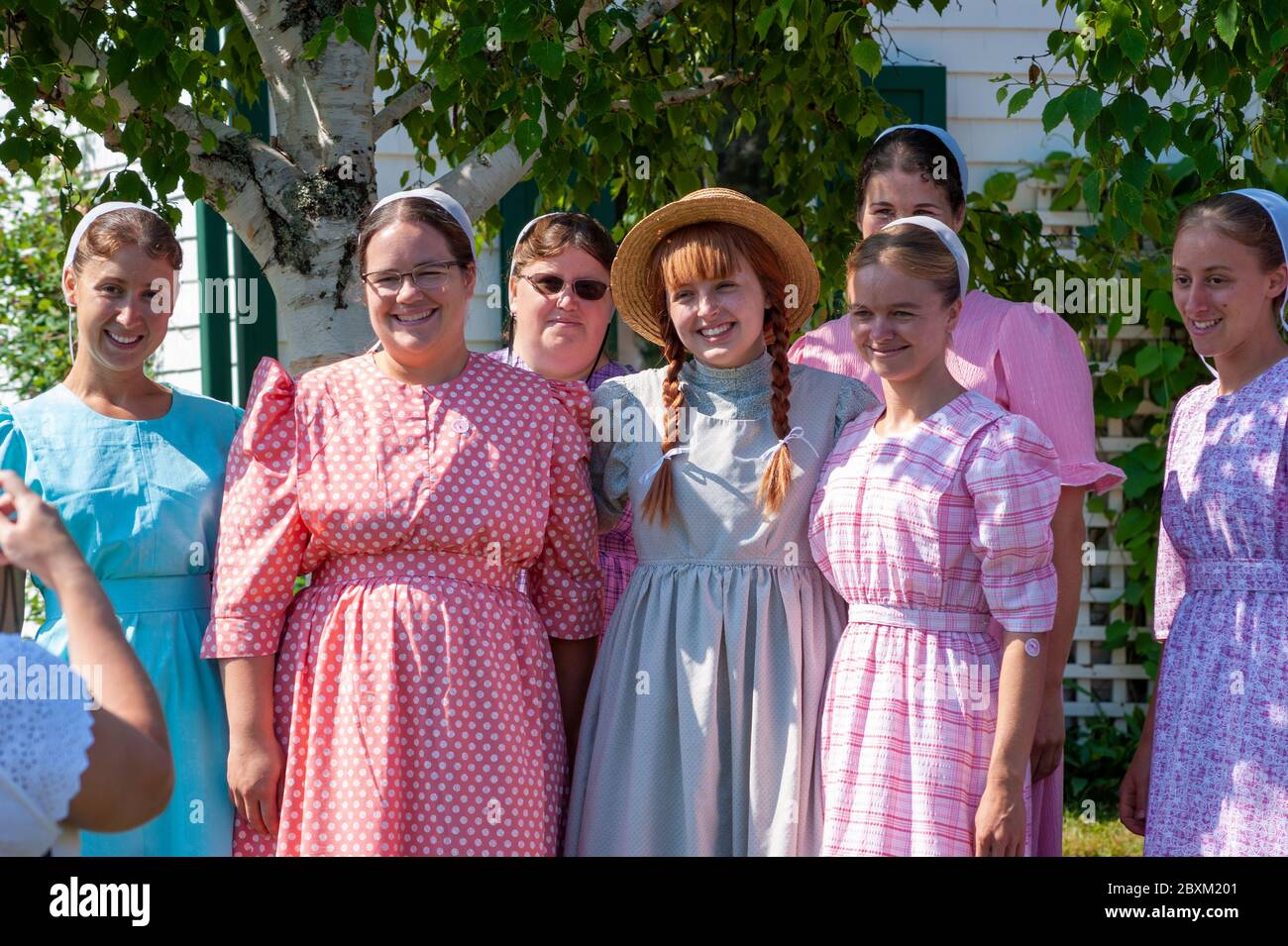 Eine Gruppe von Amish-Mädchen besucht Green Gables und posiert für einen Schnappschuss mit einer Schauspielerin in der fiktiven Figur von Anne Shirley. Cavendish, PEI, Kanada. Stockfoto