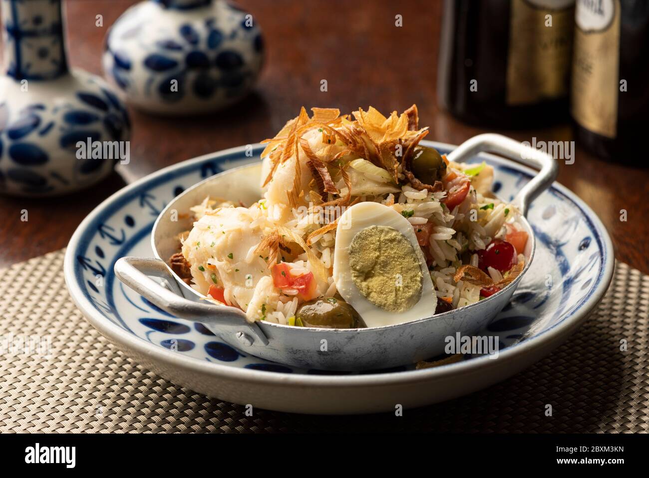 Kabeljau Fisch Bacalhau mit Reis, Zwiebeln Eier Olivenöl - portugiesisch traditionelle Lebensmittel auf Holztischunterlage und verschwommener Hintergrund Stockfoto