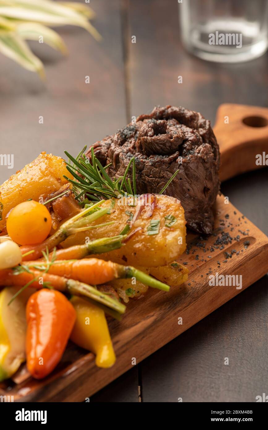 Flanke flaches Eisen Rock Steak mit Gemüse auf einem Holzbrett und verschwommener Hintergrund Stockfoto