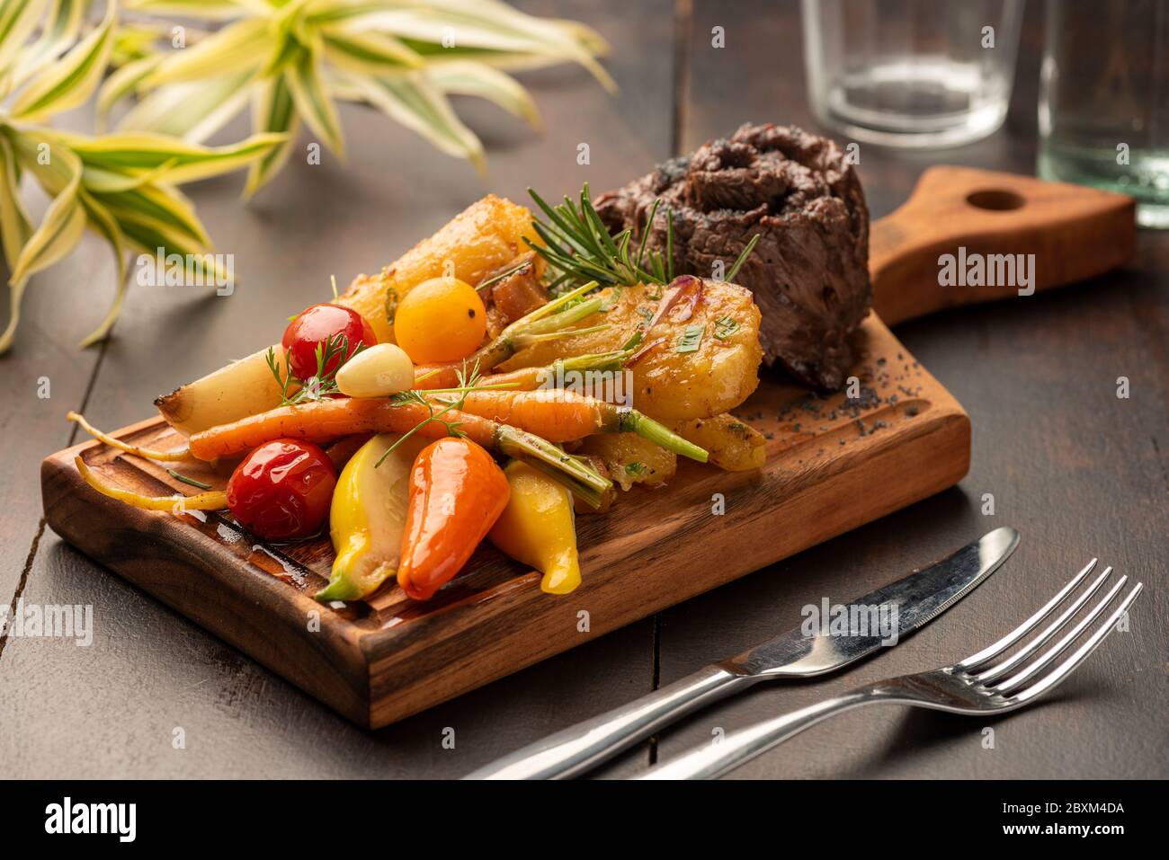 Flanke flaches Eisen Rock Steak mit Gemüse auf einem Holzbrett und verschwommener Hintergrund Stockfoto