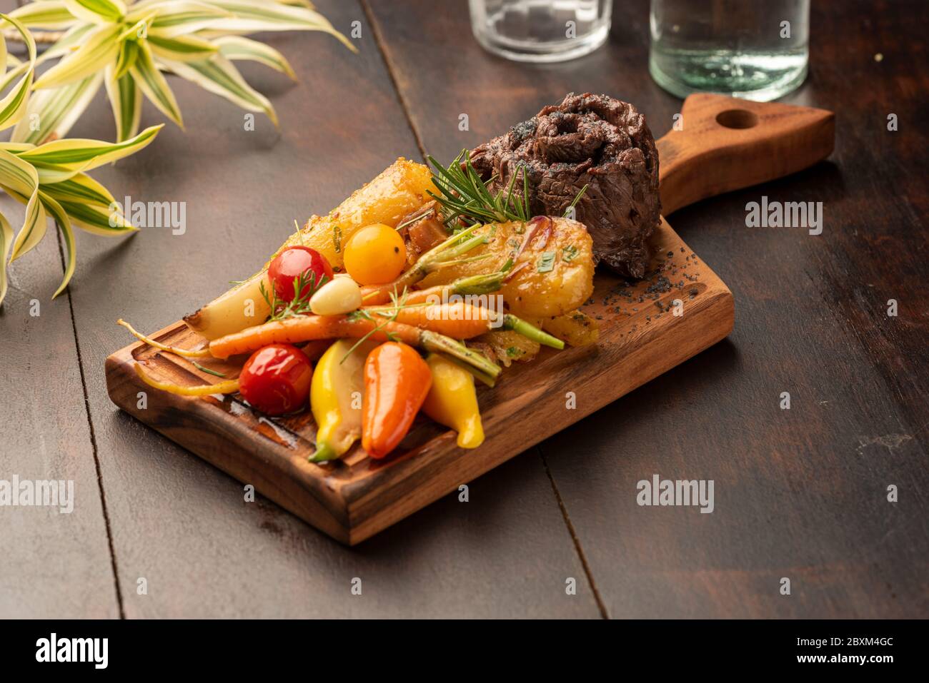 Flanke flaches Eisen Rock Steak mit Gemüse auf einem Holzbrett und verschwommener Hintergrund Stockfoto