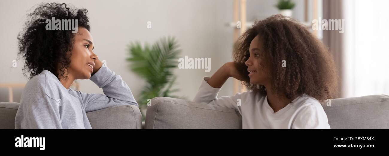 Afrikanische Mutter im Gespräch mit Tochter auf Couch zu Hause sitzen Stockfoto