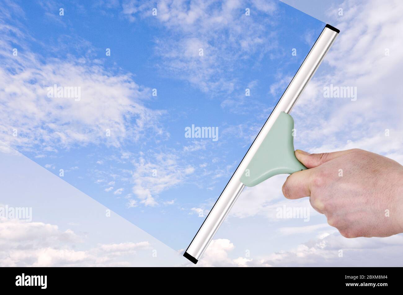 Transparenzkonzept. Hand mit einem Rakel, der dumpfen Himmel in Blau verwandelt Stockfoto