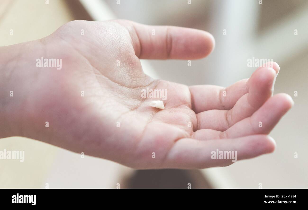 Kind hält abgefallenen Milchzahn auf der Handfläche. Nahaufnahme. Stockfoto