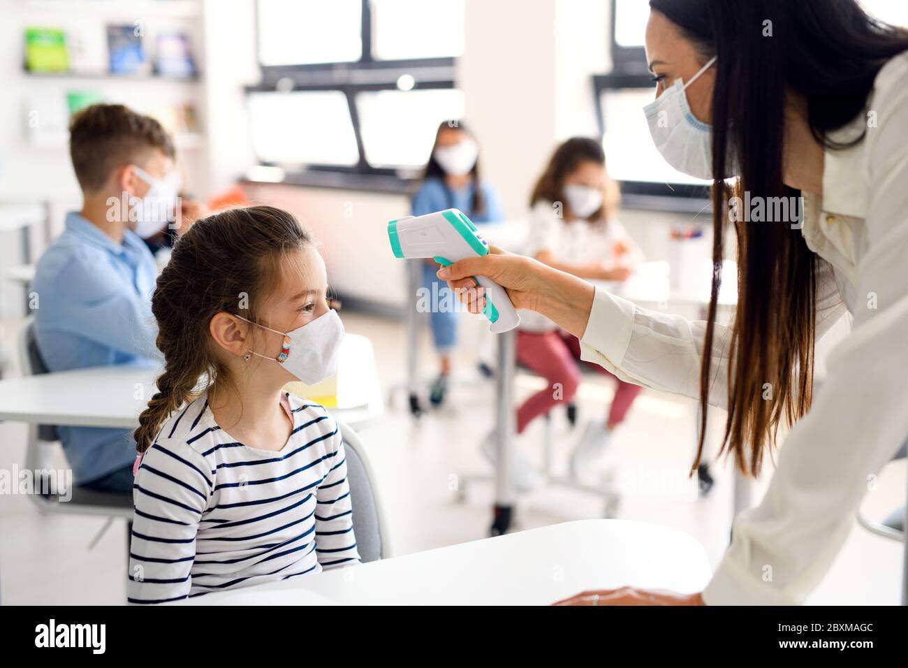 Lehrer, Kind mit Gesichtsmaske in der Schule nach Covid-19 Quarantäne, Temperaturmessung. Stockfoto
