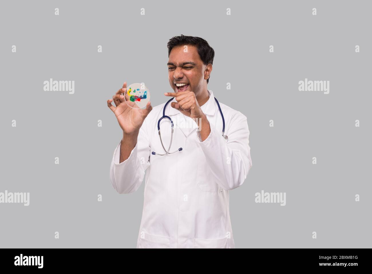 Doktor aufgeregt zeigt auf Petrischale isoliert. Indian Man Doktor Medizin, Wissenschaftskonzept Stockfoto