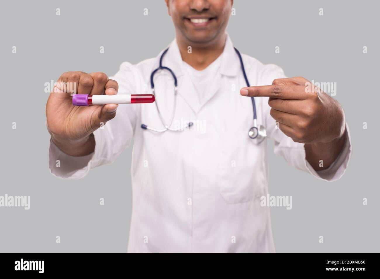 Arzt zeigt auf Bluttubus-Analyse Horisontal isoliert. Indischer Mann Doktor mit Blutprobe Porträt. Wissenschaft, Medizinisches Konzept. Stockfoto