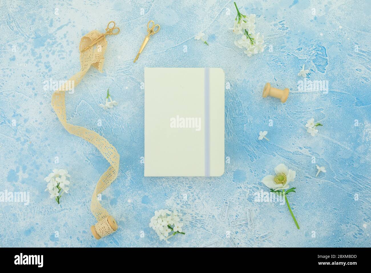 Sommer Komposition von Blumen mit weißem Tagebuch, Quaste und goldene Schere auf blauem Hintergrund. Flach liegend, Draufsicht Stockfoto