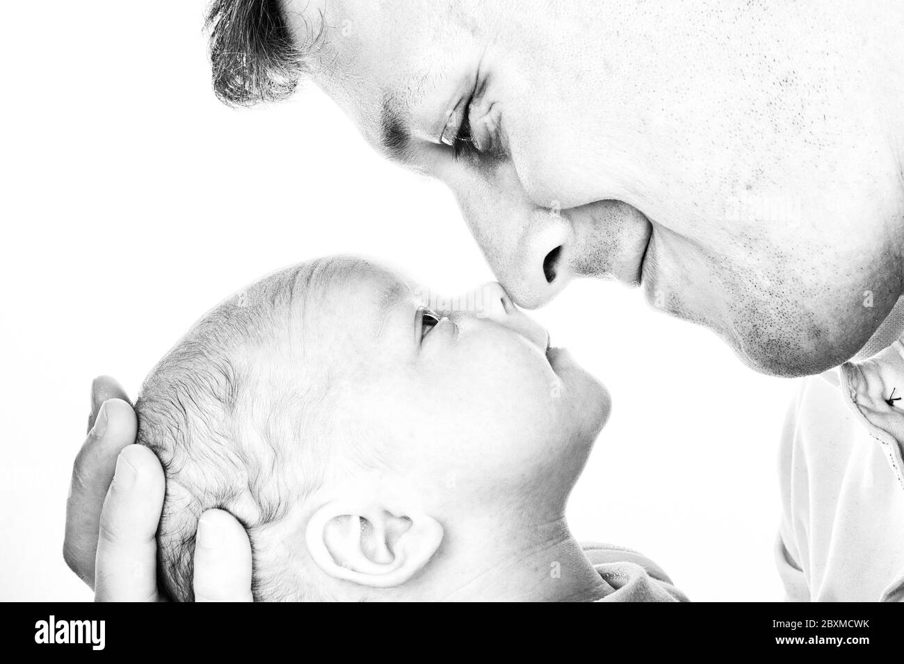 High Key Porträt in schwarz-weiß, von einem Vater liebevoll umarmt seinen neugeborenen Sohn Stockfoto