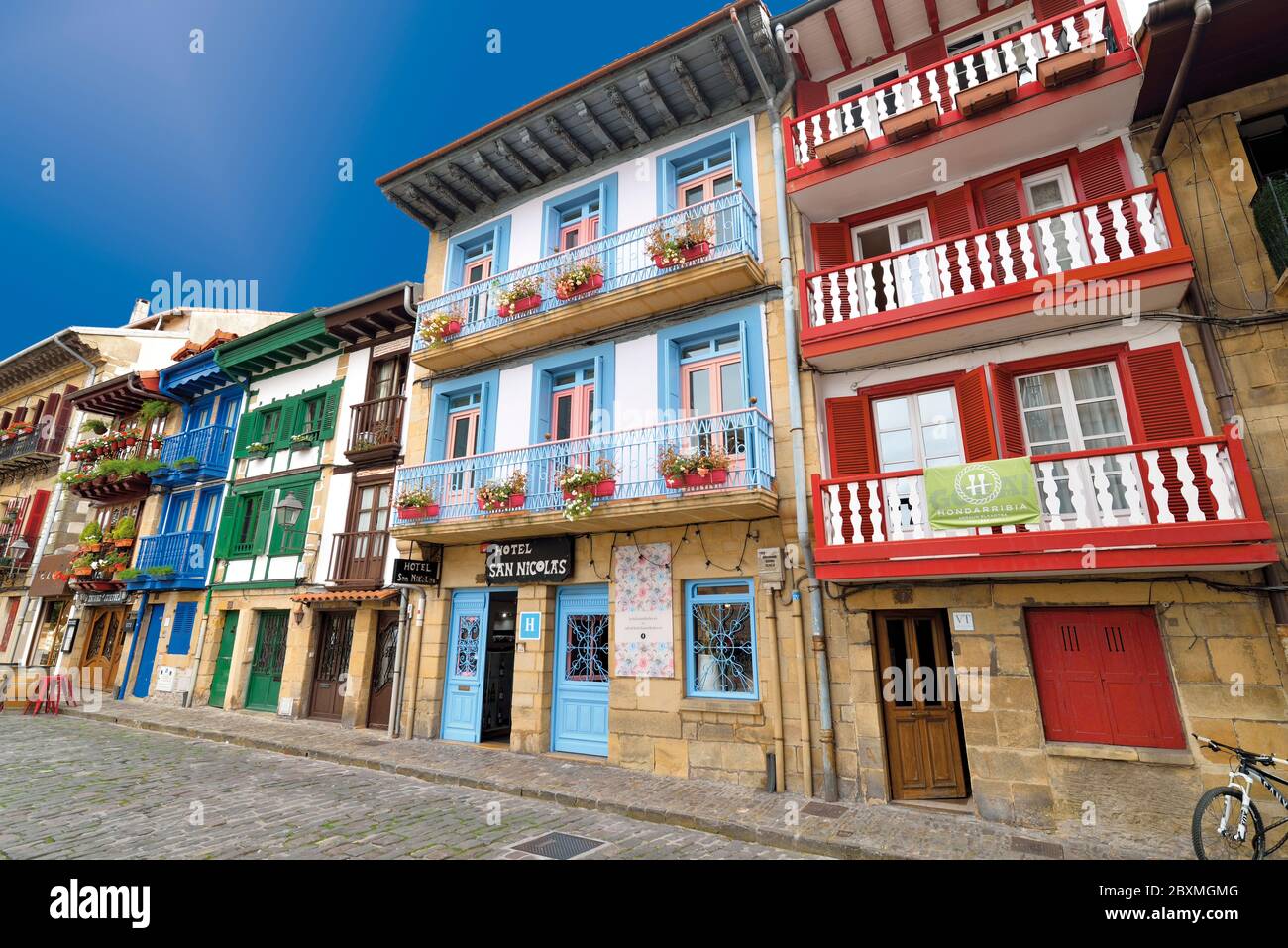 Bunte Stadthäuser mit Balkonen und roten und blauen Fenstern säumen eine mittelalterliche Straße im Stadtzentrum von Hondarribia Stockfoto