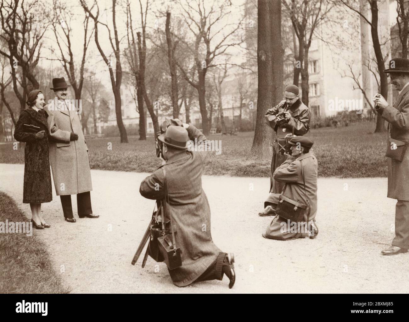 Pressefotografen. Ein Paar hat während ihres Spaziergangs angehalten, um sich von einer Gruppe von Pressefotografen fotografieren zu lassen. 1930er Jahre Stockfoto