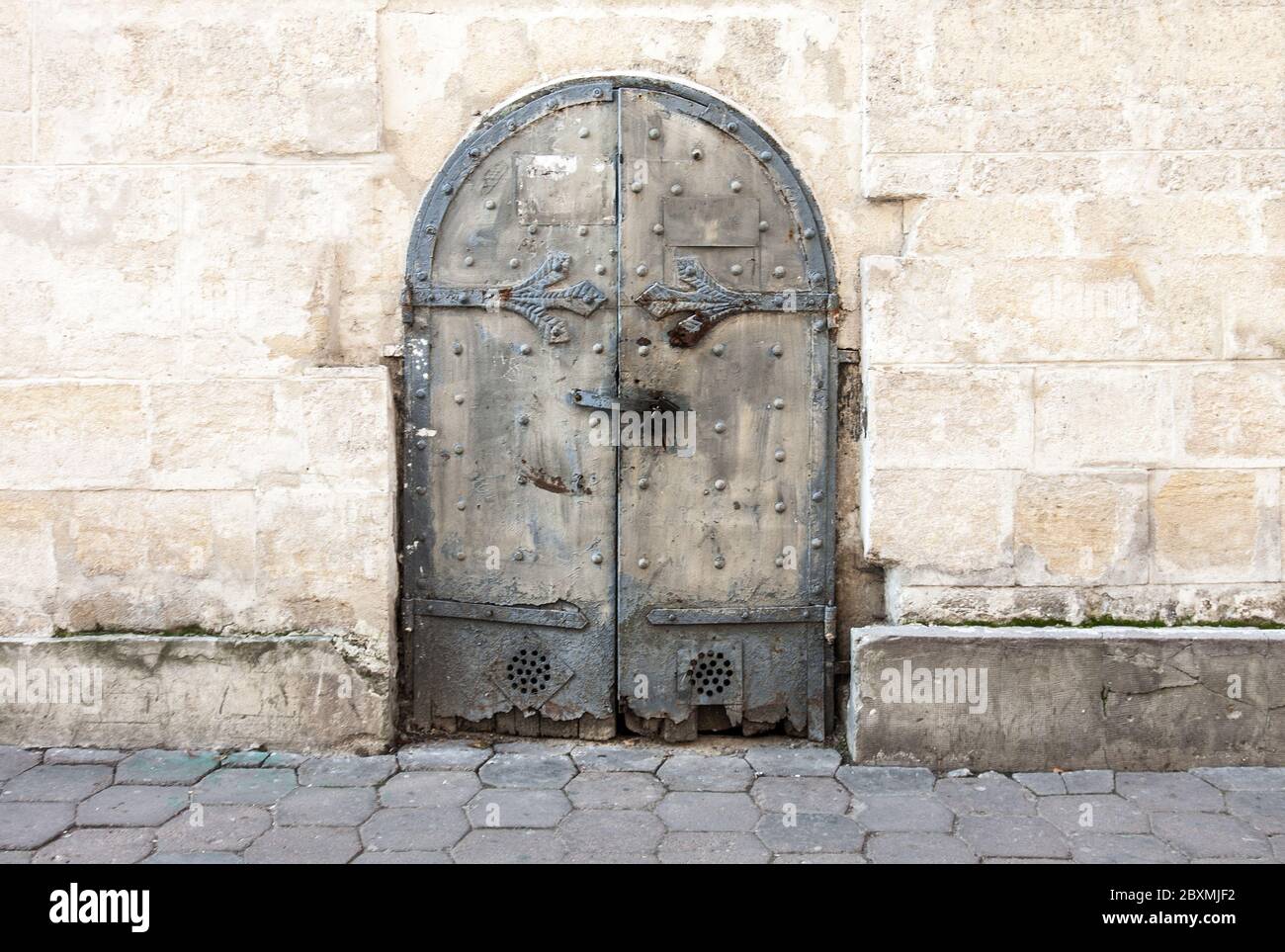 Alte Metalltür an der Wand eines Stadthauses. Ein Element der Architektur. Stockfoto