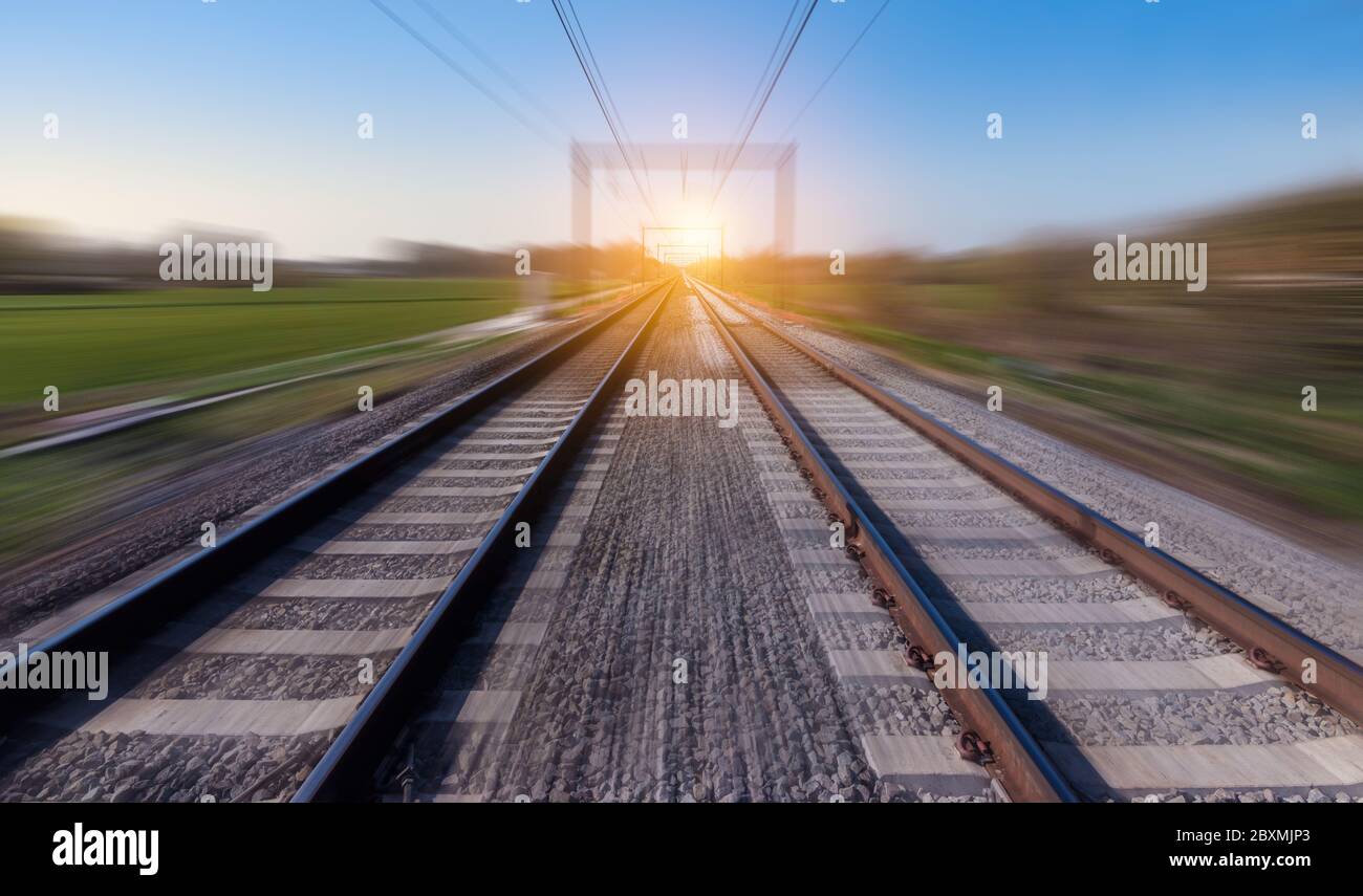 Bahnstrecke in Bewegung. Verwischte Schienenlandschaft bei Sonnenuntergang. Stockfoto