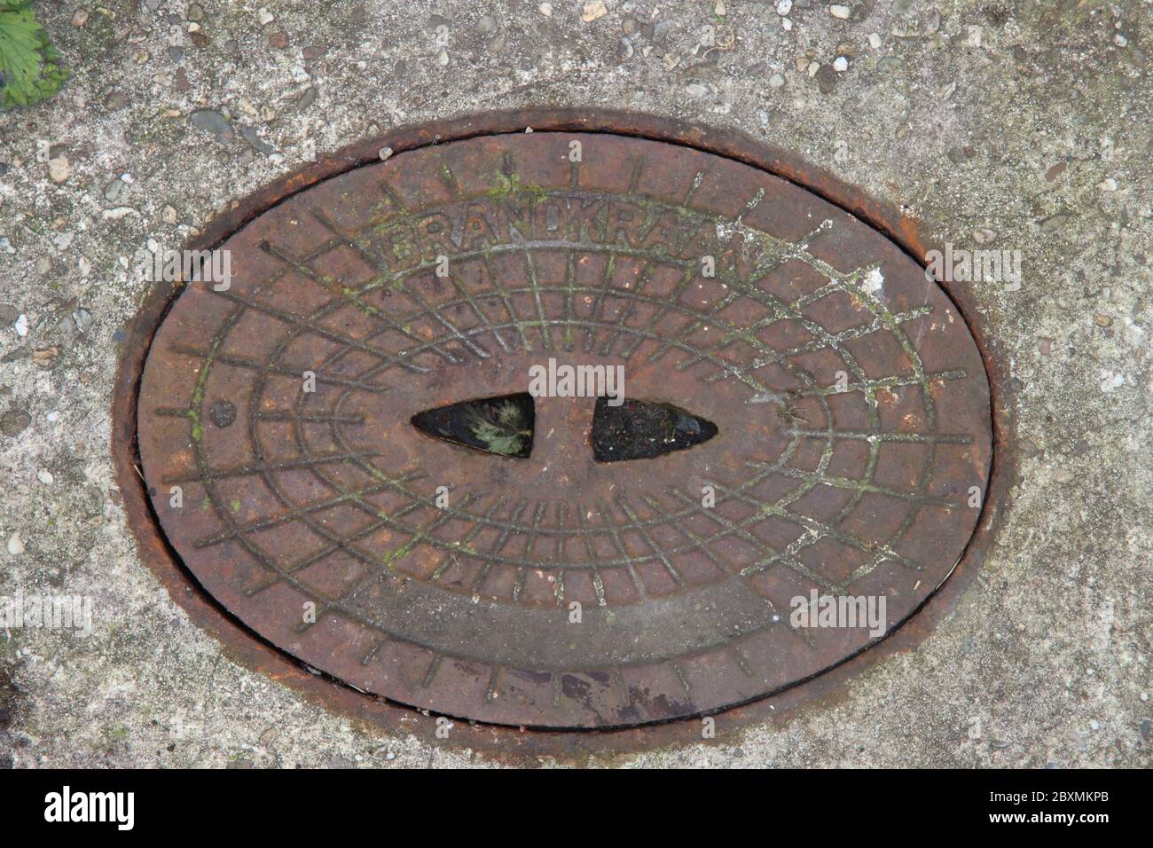 Der Deckel eines Brunnens aus Gusseisen, in dem der Hydrant versteckt ist und im Brandfall verwendet werden kann Stockfoto