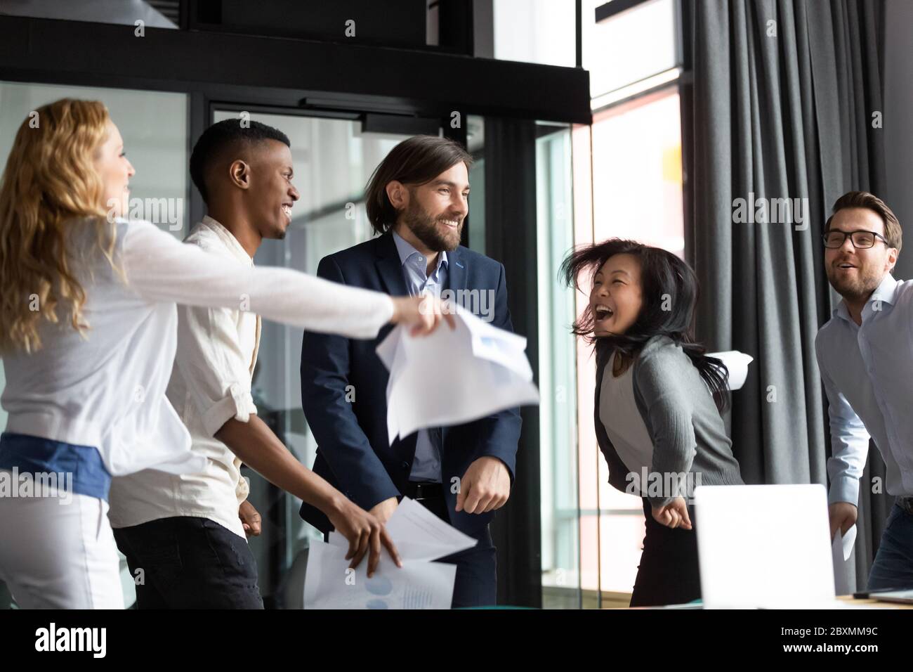 Multirassische Mitarbeiter schreien vor Freude tanzen Spaß am Arbeitsplatz Stockfoto