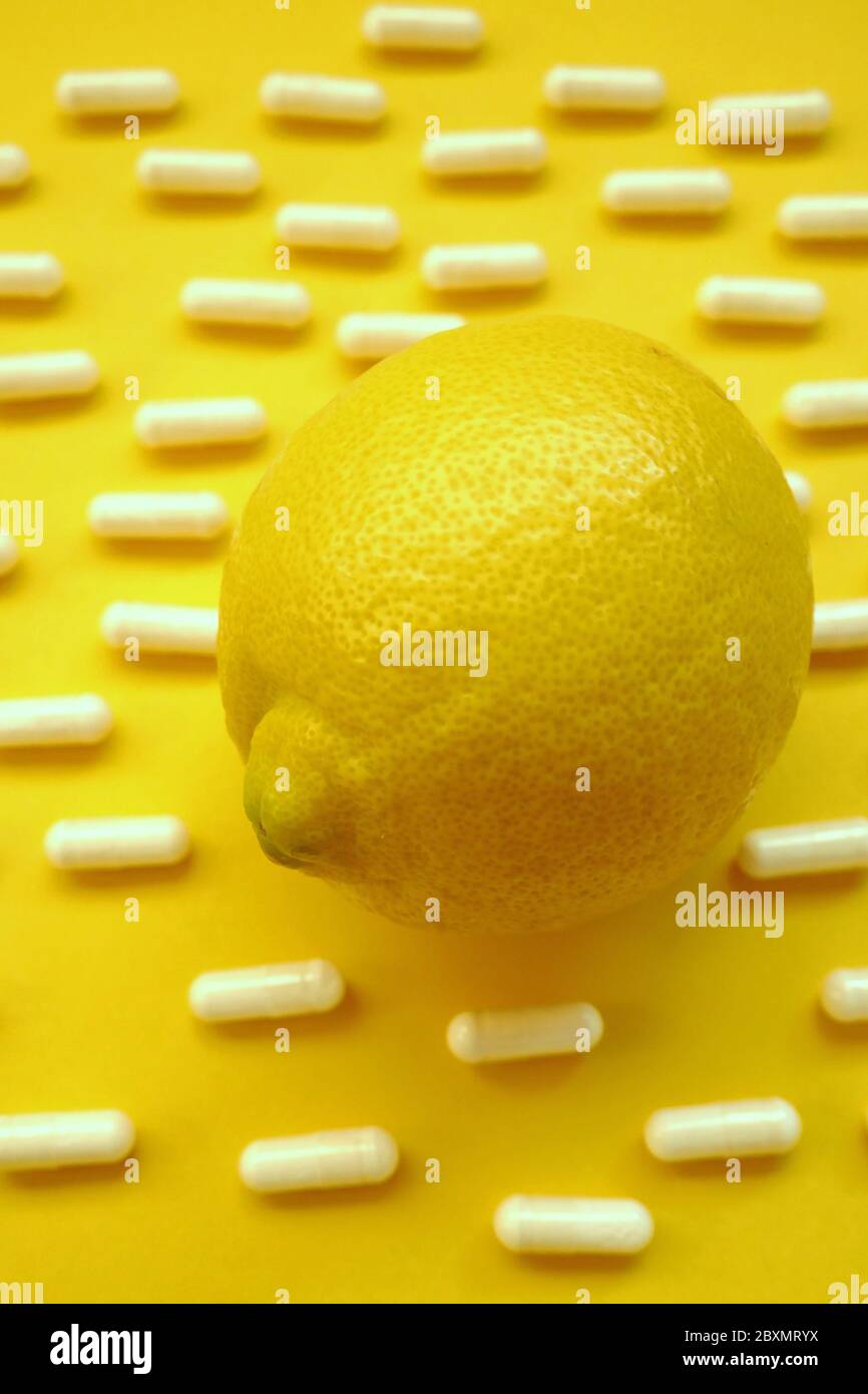 Vitamin C-Konzept. Zitrusfrüchte Zitrone und medizinische Kapseln auf einem hellgelben Hintergrund.Prävention von Erkältungen und Grippe. Stärkung der Immunität. Stockfoto