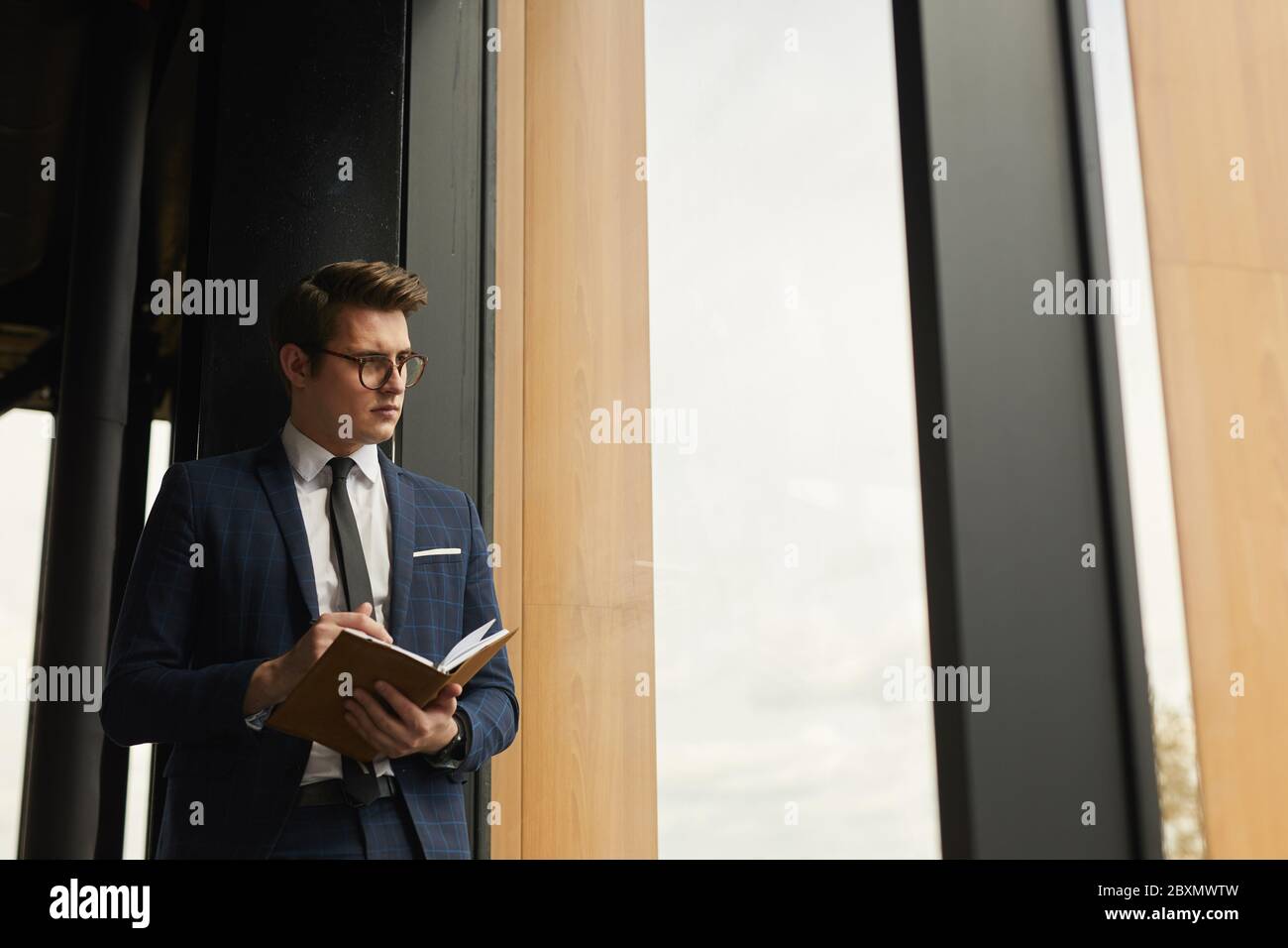 Taille oben Porträt des Business Agent hält Notebook stehend durch modernes Haus und Blick weg, Kopierer Raum Stockfoto