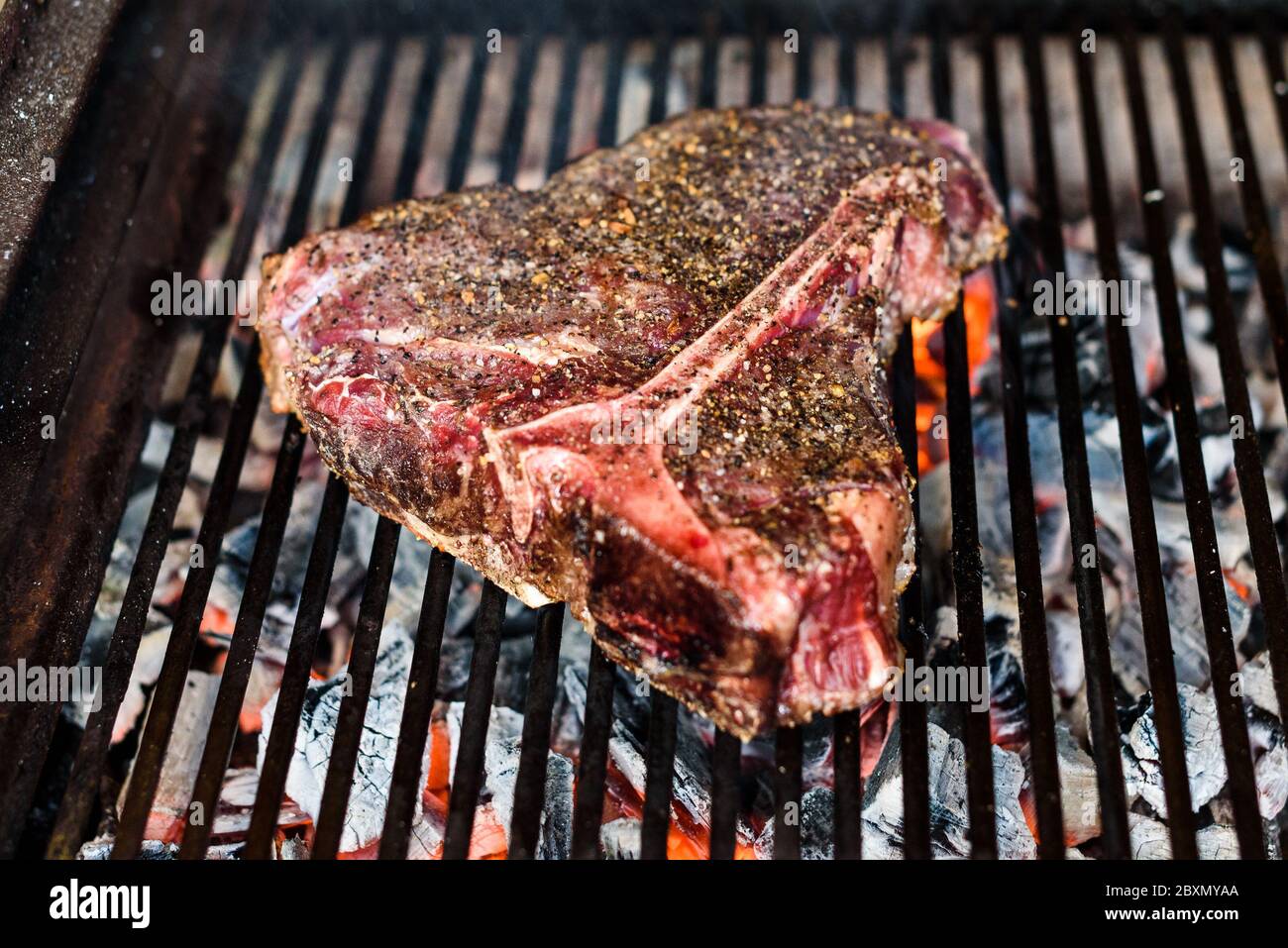 Grillen Big T Bone Steak auf natürlichen Holzkohle Grill. Vorbereitung  eines großen Steak auf natürlichen Brennholz Grill im Kamin draußen.  Grillspuren am Feinkostladen Stockfotografie - Alamy
