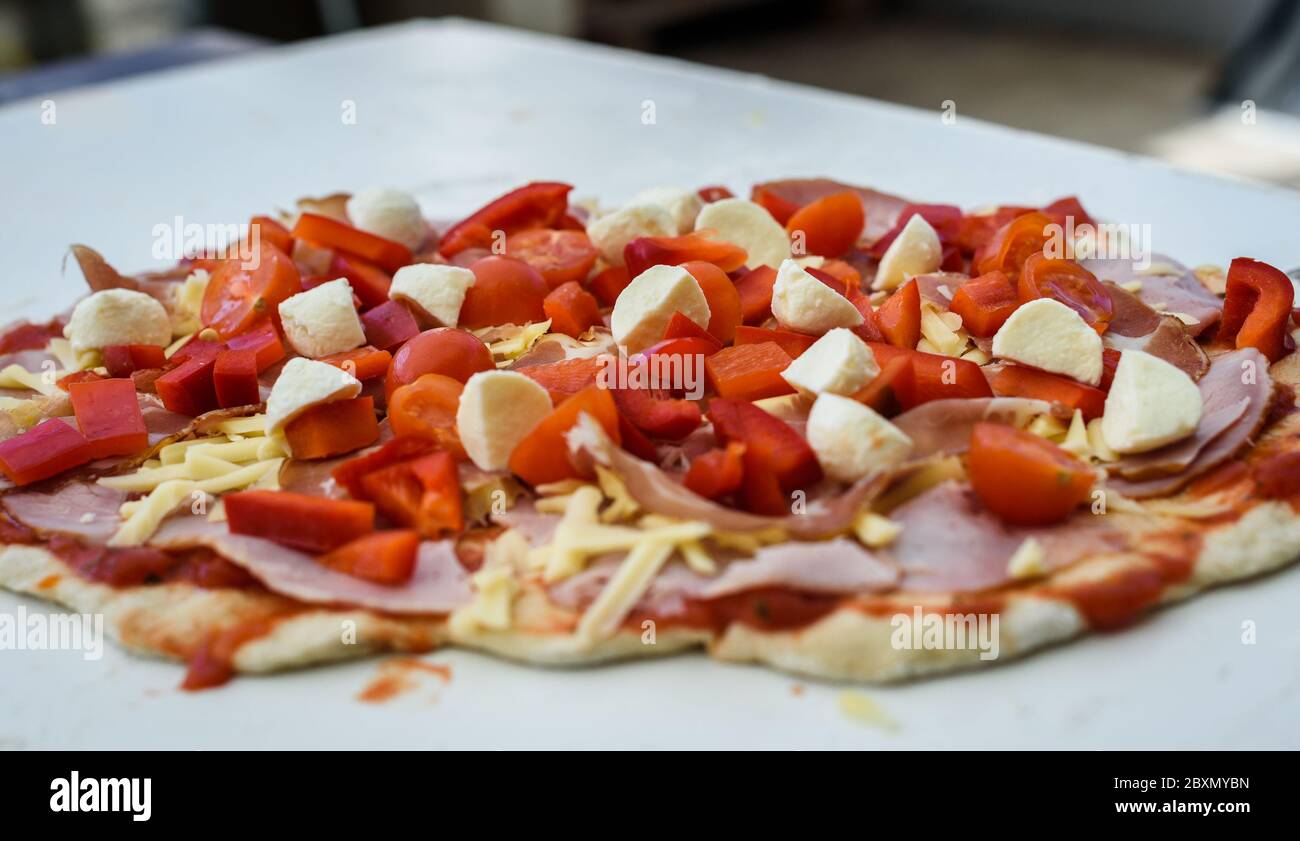 Herstellung von hausgemachten italienischen Pizza im Kamin Backstein Ofen. Herstellung von Pizza und Zugabe von verschiedenen Zutaten vor dem Backen im Kamin. Raw Stockfoto