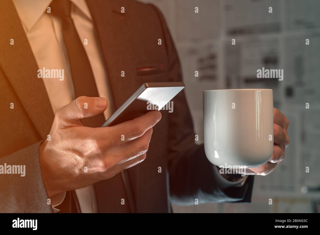Geschäftsmann trinken Kaffee und mit Handy in gefälschten Nachrichten infodemic Konzept mit Boulevardzeitung Zeitung Seiten im Hintergrund Stockfoto