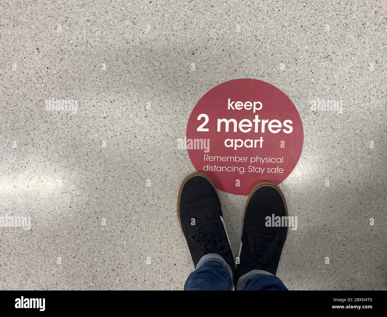 Ein sozialer Distanziersticker auf dem Boden warnt die Menschen, 2 Meter auseinander zu bleiben Stockfoto