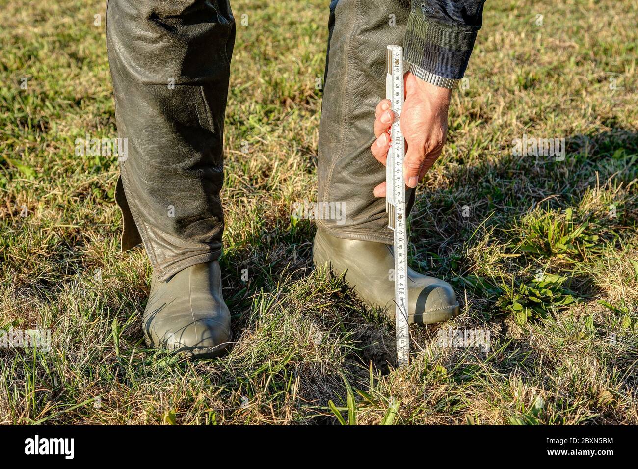 Durch den Klimawandel wird in Deutschland der Boden im Feld aufgerissen. Um zu zeigen, wie tief die Risse sind, setzt ein Landwirt seine Zoll-Regel in einem der cra Stockfoto