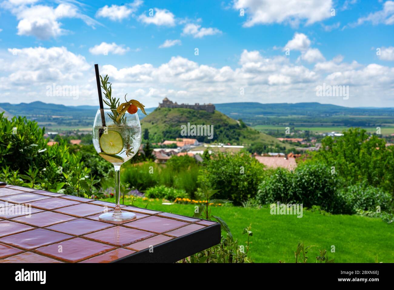 Trinken Gin Tonic Cocktail mit einem schönen Blick auf die sumeg Fort auf einem Hügel in der Mitte der Stadt Stockfoto