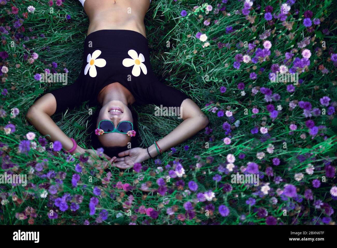 Junge schöne Mädchen in Sonnenbrille auf dem Maisblüten Feld liegen. Outdoor-Portrait, Sommer Spaß Konzept. Lifestyle-Fotografie. Stockfoto