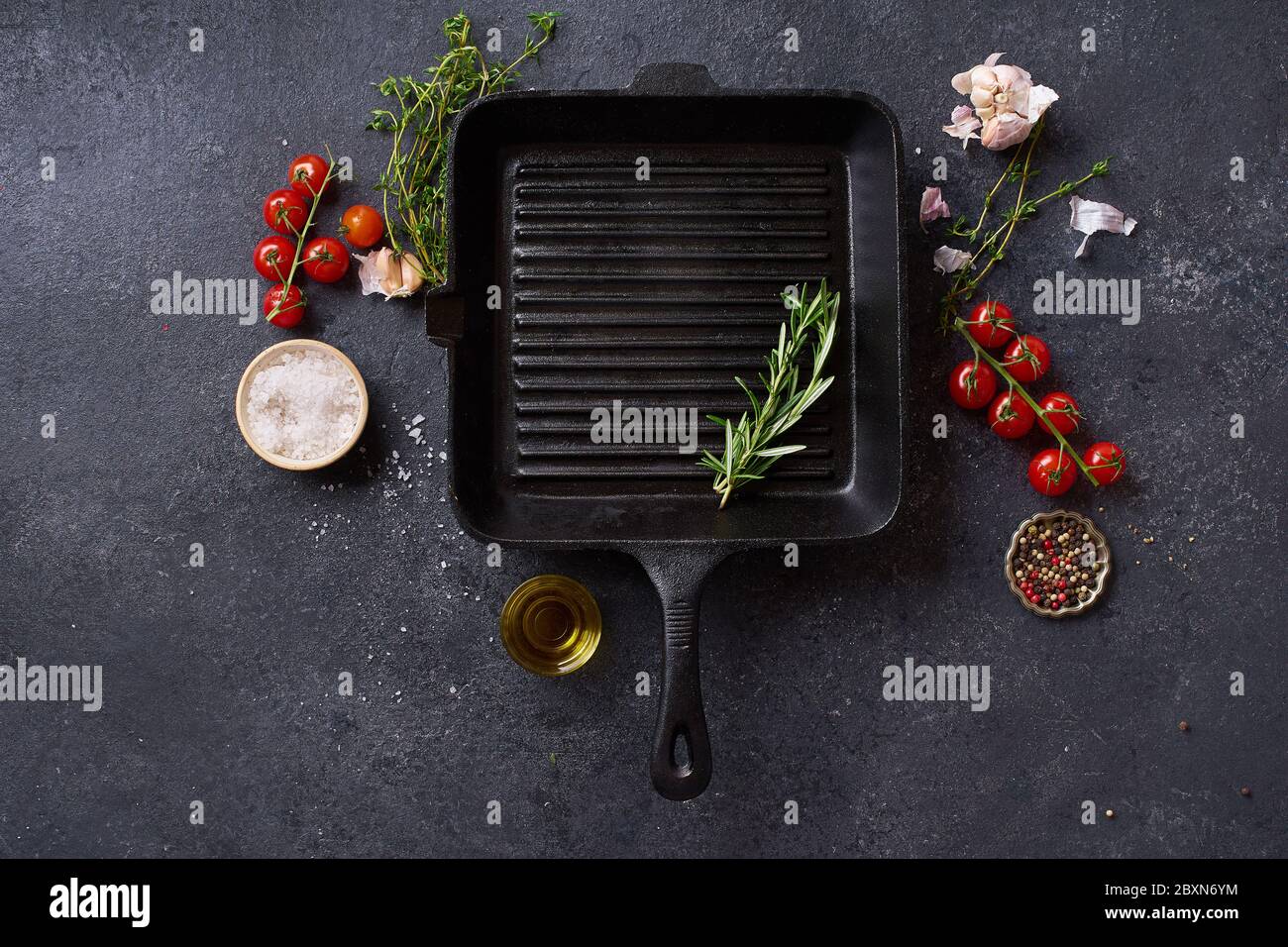 Flat Lay Draufsicht schwarz Gusseisen Pfanne für Grill. Bratpfanne mit Kochzutaten und Gewürzen auf Betongrund mit Kopierfläche Stockfoto