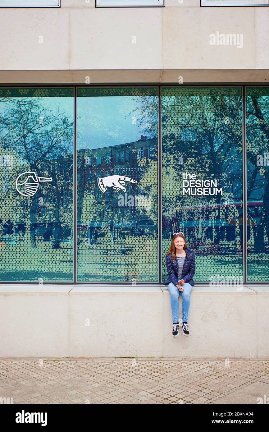 Junges Mädchen, das vor dem Design Museum, Kensington High St, London, sitzt Stockfoto